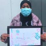 A student holds a sign that says welcome in Somali